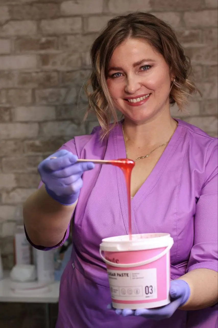 Скопич Ірина з цукровою пастою на шпателі в правій руці та платиковою банкою в лівій.